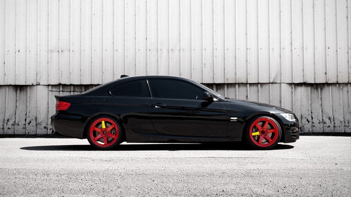 Black BMW E92 coupe with red wheels on asphalt