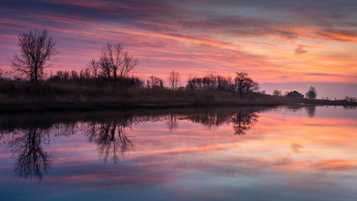 Sunset over a calm river with reflections