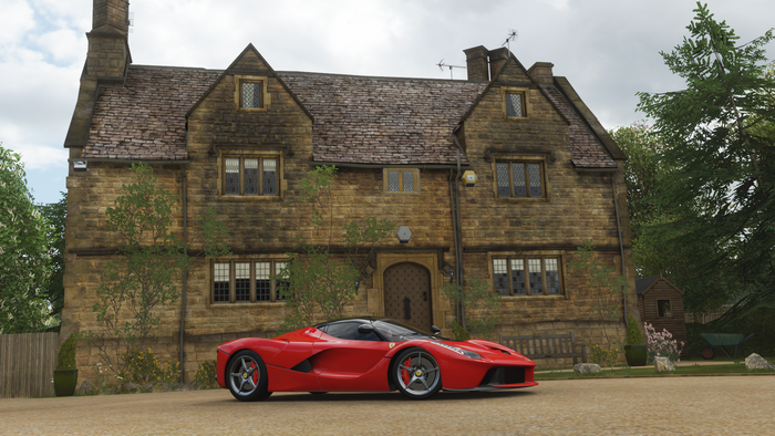 Red Ferrari LaFerrari in front of a stone house
