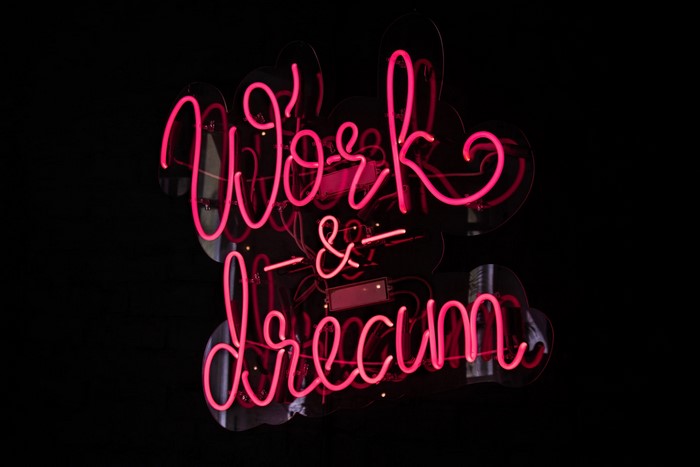 Pink neon sign that says "Work & Dream"