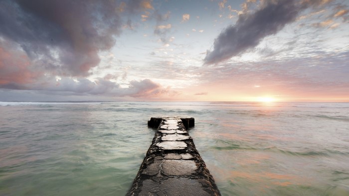 Stone pier extending into the sea at sunset