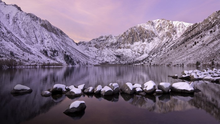 Snowy mountains reflecting in a lake at sunrise