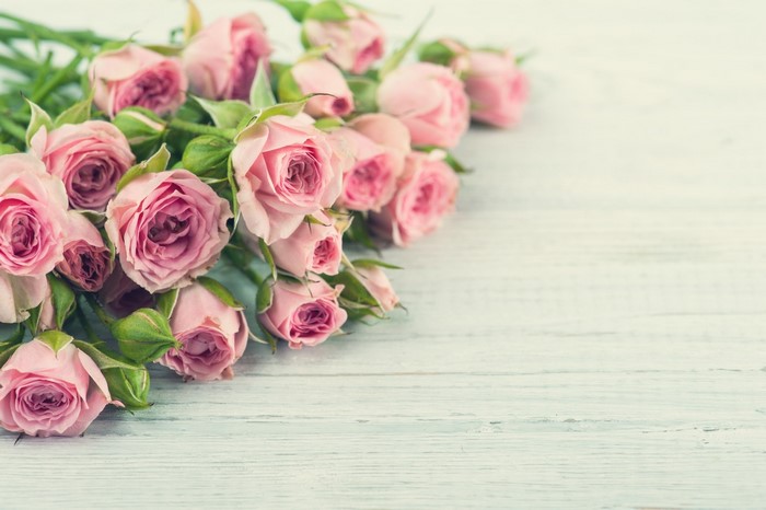 Bouquet of pink roses on a light wooden surface