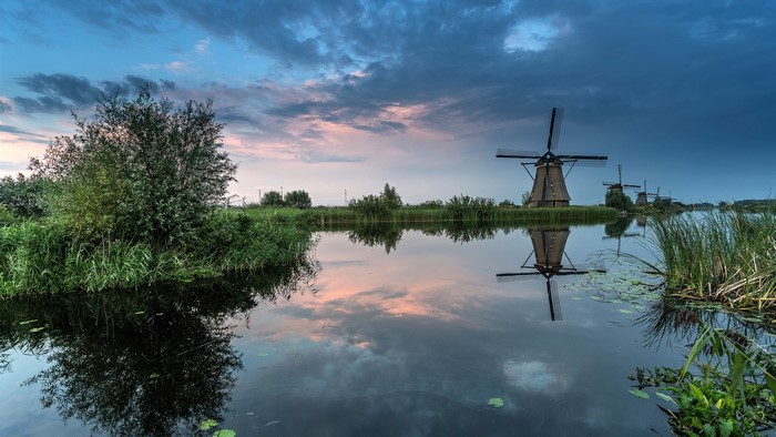Windmills reflected in water at sunset in the Netherlands