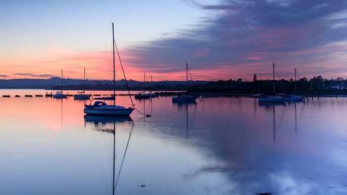 Sailboats on water at sunset with colorful sky