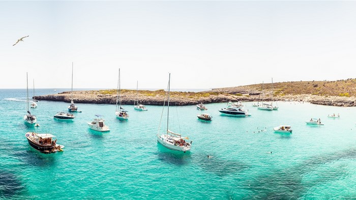 Boats anchored in a clear turquoise bay with rocky shores