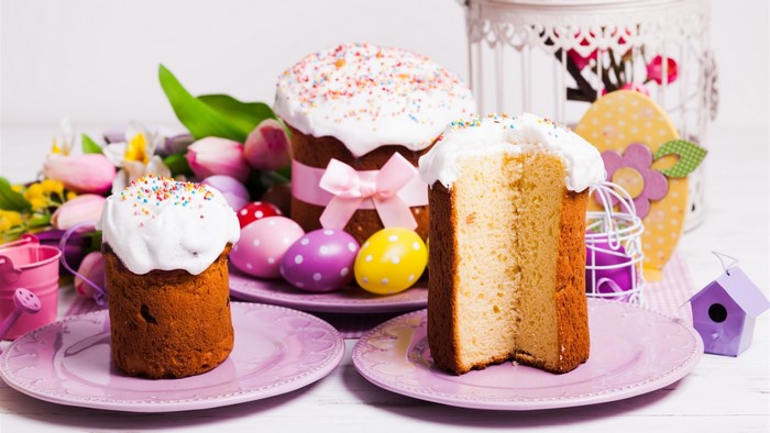 Easter cakes with frosting and sprinkles, decorated eggs, and tulips