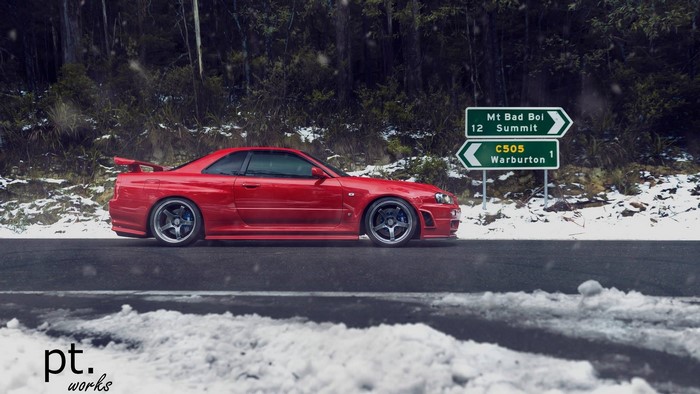 Red Nissan Skyline GT-R R34 in snow with road signs