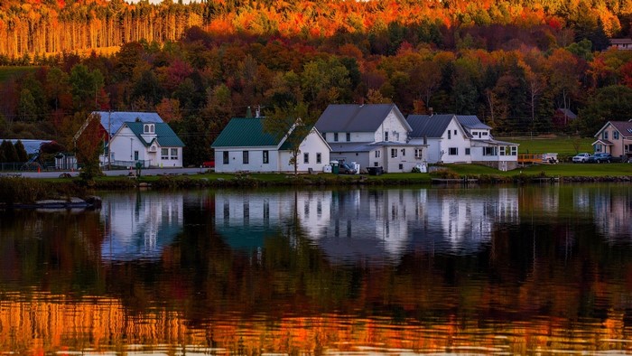 Houses reflected in a lake with autumn trees