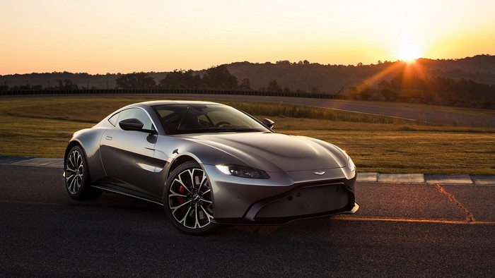 Silver Aston Martin Vantage on a race track at sunset