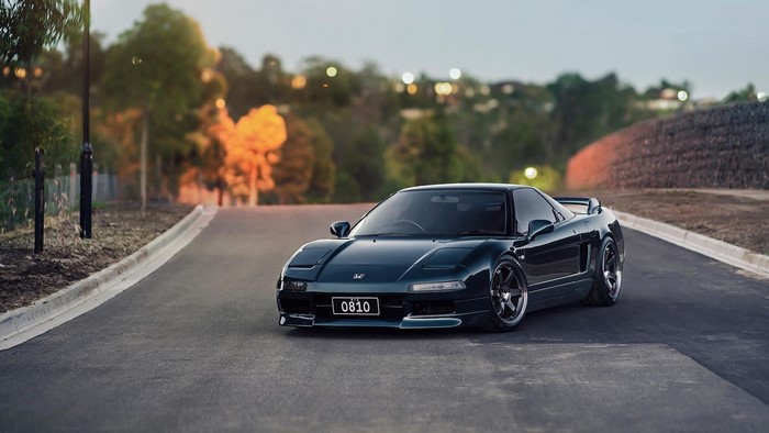 Dark blue Honda NSX mk1 with pop-up headlights on a road