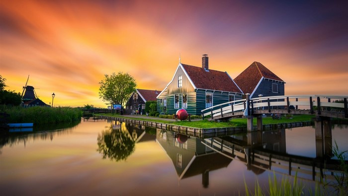 Dutch village with windmill and canal at sunset
