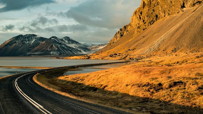 Road curving along a lake with mountains