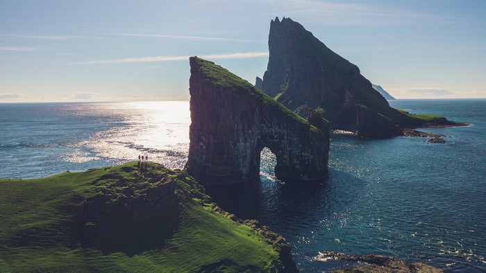 Arch rock formation in the ocean with people on cliff