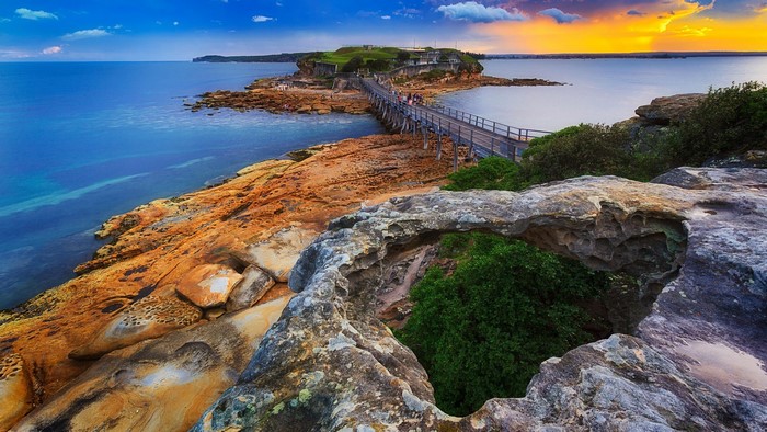 Wooden bridge over rocks to island at sunset