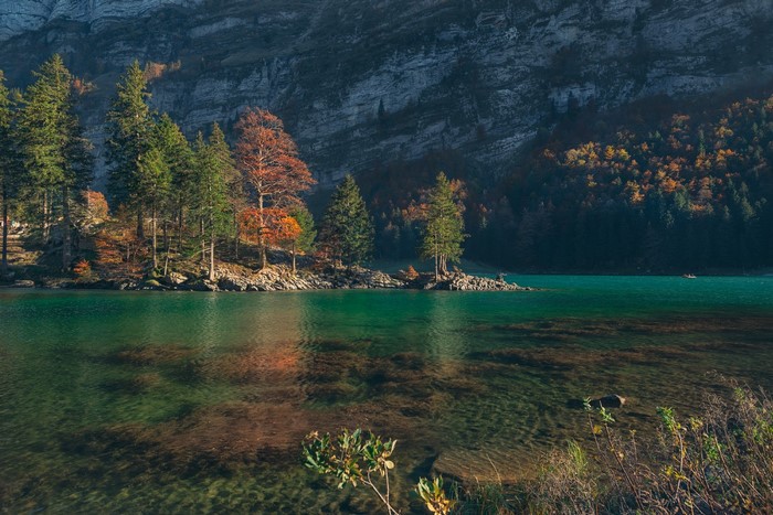 Turquoise lake with trees and mountains in autumn