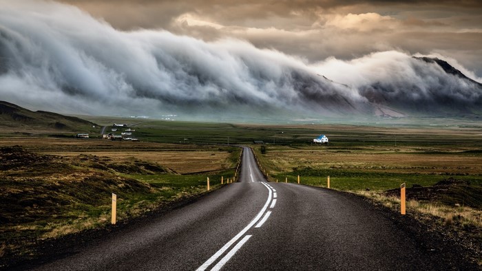 Road leading to mountains with dramatic clouds