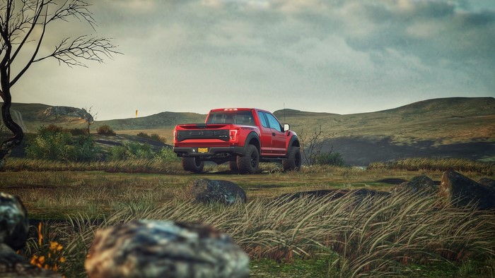 Red Ford F-150 Raptor in a grassy field