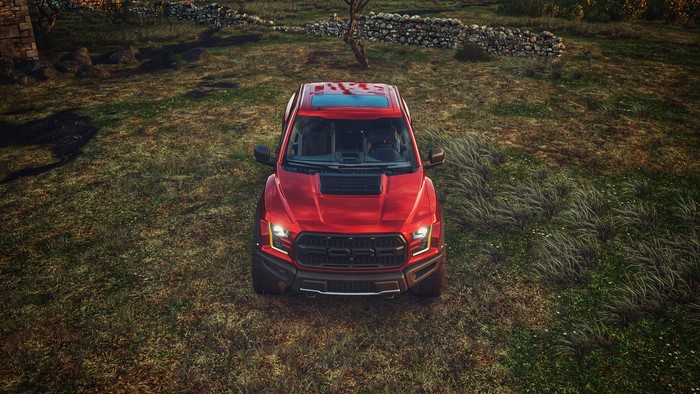 Red Ford F-150 Raptor in a grassy field