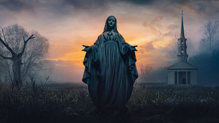 Statue of Mary in a misty field at sunset