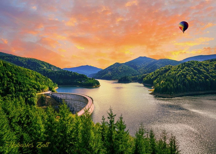 Dam and hot air balloon over lake in Romania