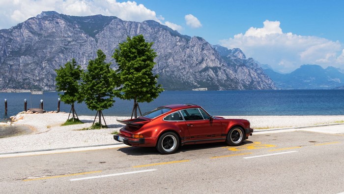 Red Porsche 930 Turbo parked by Lake Garda