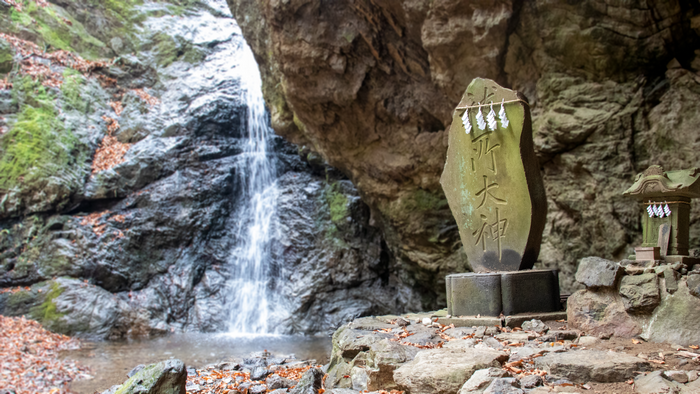 Stone monument and shrine by a waterfall in Japan