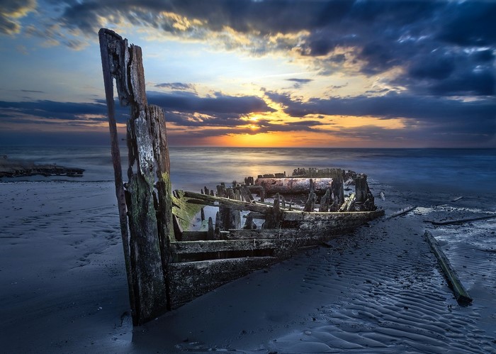 Shipwreck on a beach at sunset