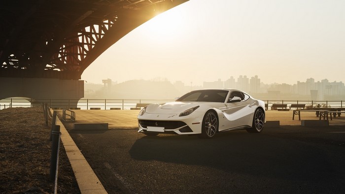 White Ferrari F12berlinetta parked under a bridge at sunset