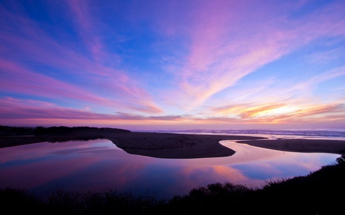 Sunset over a river estuary meeting the sea