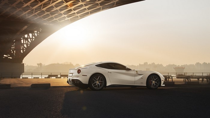 White Ferrari F12berlinetta parked under a bridge at sunset