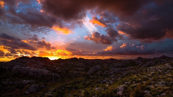 Sunset over rocky landscape with dramatic clouds