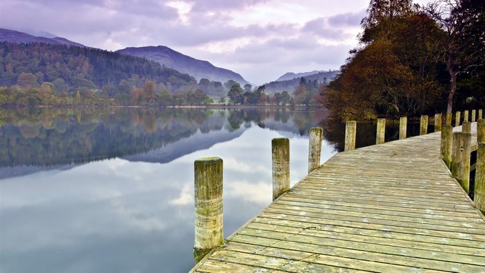 Wooden pier on a lake with reflections of hills and trees