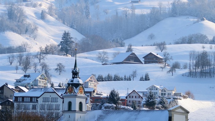 Snowy village with church tower and mountains