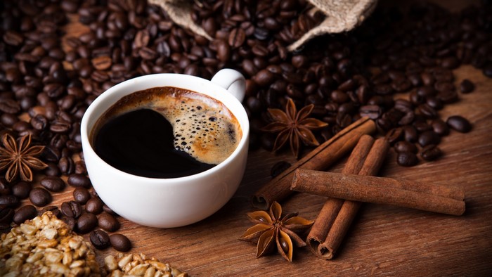 Cup of coffee with coffee beans, cinnamon sticks, and star anise