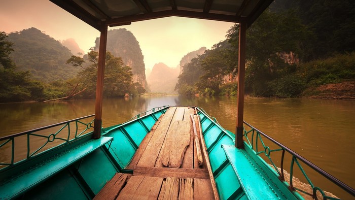 Boat on a river with mountains and mist in Vietnam