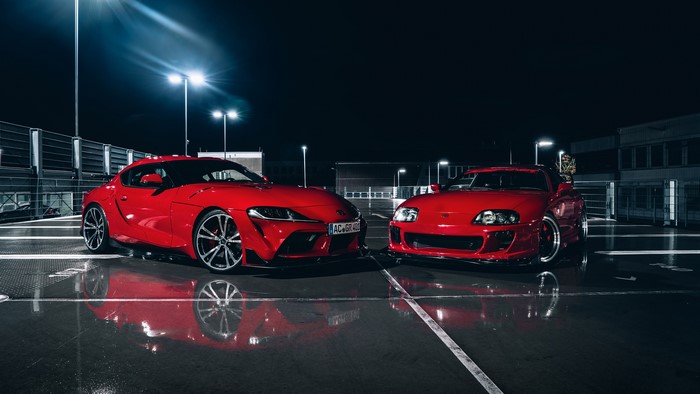 Two red Toyota Supra cars parked at night