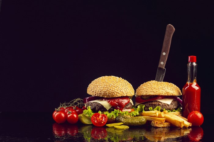 Two burgers with fries, tomatoes, and ketchup