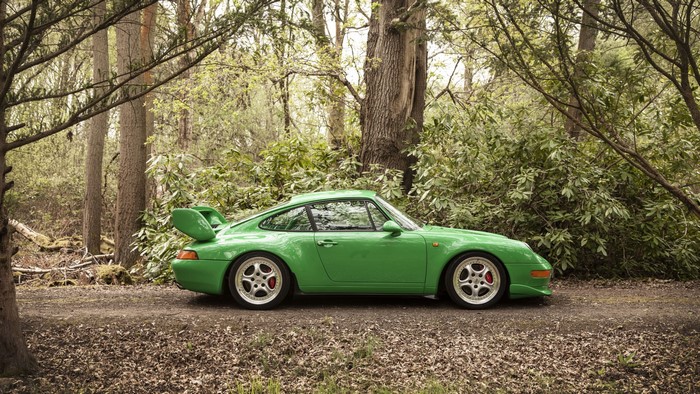Green Porsche 911 993 parked on a dirt road in a forest