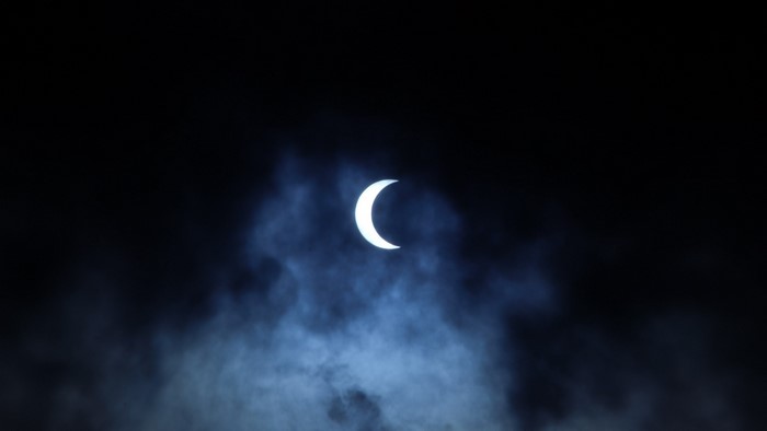 Crescent moon partially obscured by clouds at night