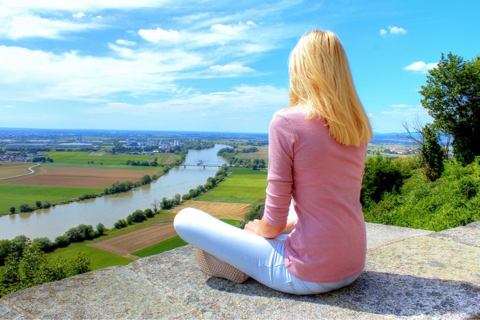 Woman sitting on a stone wall overlooking a river valley