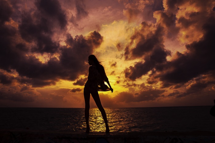 Silhouette of a woman against a dramatic sunset sky