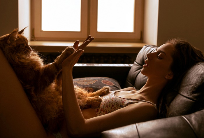 Woman and Maine Coon cat on a couch
