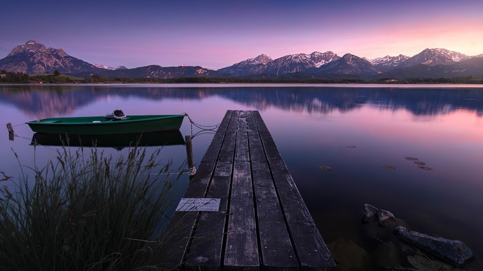 Boat on a calm lake with mountains at sunset