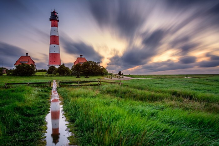 Lighthouse with red and white stripes and reflection in water