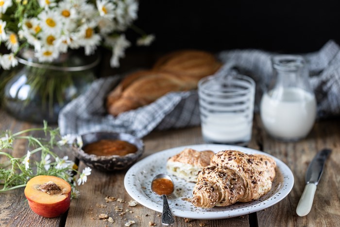 Breakfast with croissants, jam, milk, and fruit