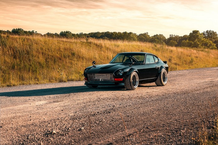 Black Datsun 240Z with bolt-on fender flares on a dirt road