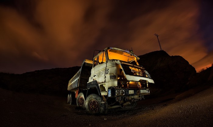 Abandoned dump truck at night with orange clouds