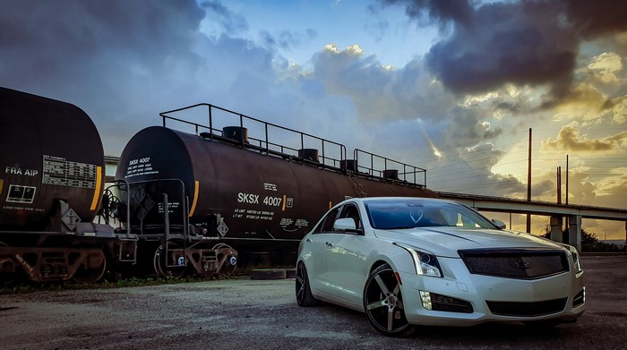 White Cadillac ATS parked next to train cars
