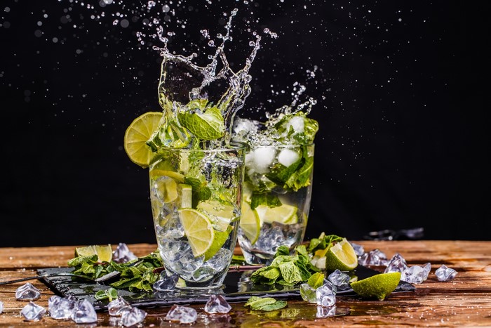 Two mojitos with lime and mint splashing